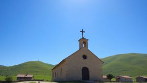 Biserică veche pe un deal, cu case în jur.